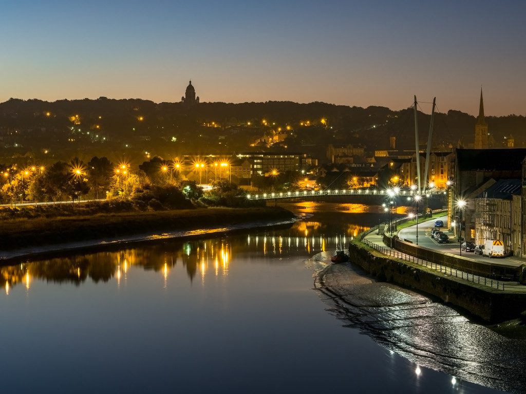 Taken at dawn from Carlisle Railway footbridge looking down River Lune with Ashton Memorial on skyline and Millenium footbridge lights in centre of image