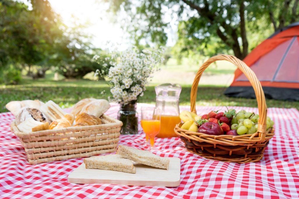 picnic bread croissant basket with fruit on red white cloth and vase flower with jar of orange juice
