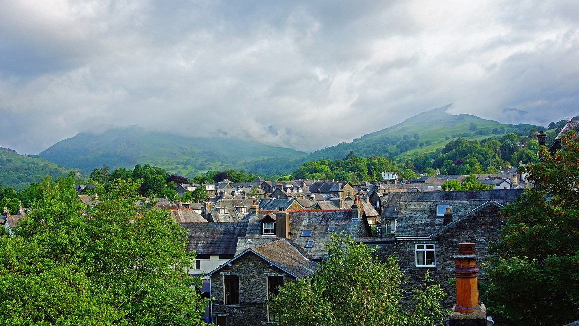 Looking over the roof tops of the town of Ambleside towards the start of the mountain range called The Langdale Pikes, The Lake District, Cumbria, England, United Kingdom