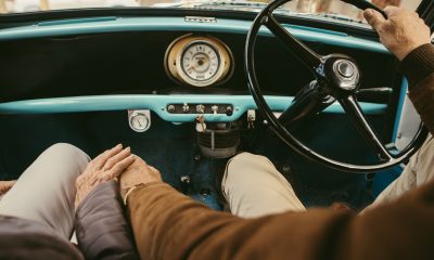 Close up of a senior couple holding hands while driving a car. Old man driving the car with woman sitting on passenger seat holding his hand.