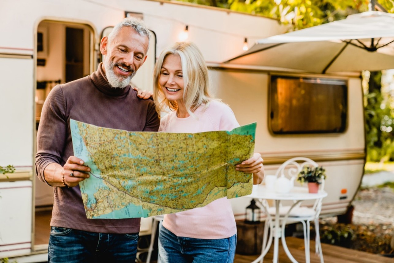 couple holding a map Infront of a towed caravan